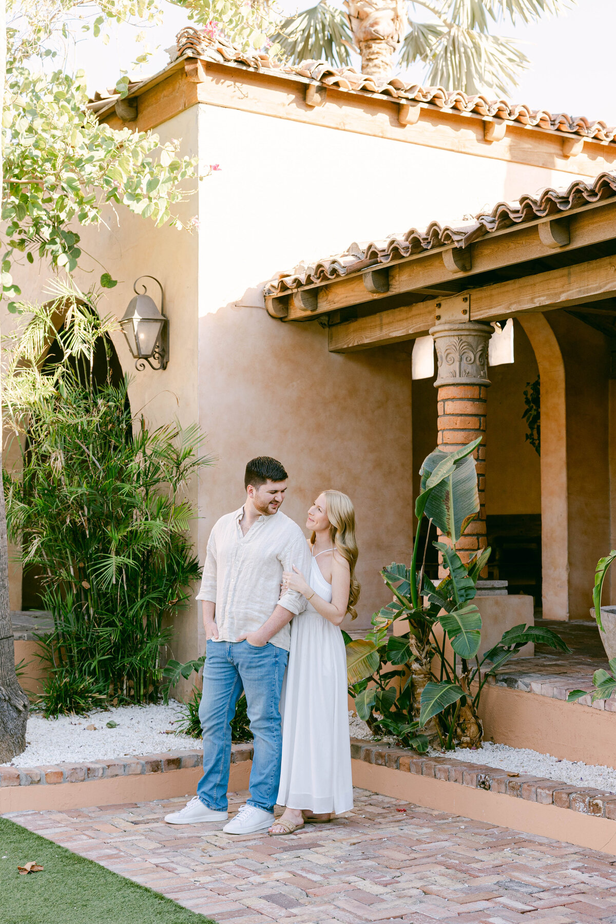 Couple hugging while walking along the Verandera Lawn at Royal Palms during engagement session