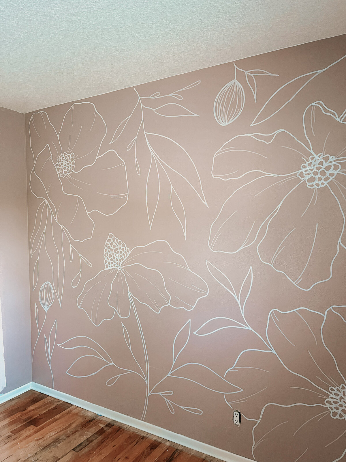 A nursery wall with white modern florals hand drawn by local artist representing full service design and calligraphy by Life in Letters.