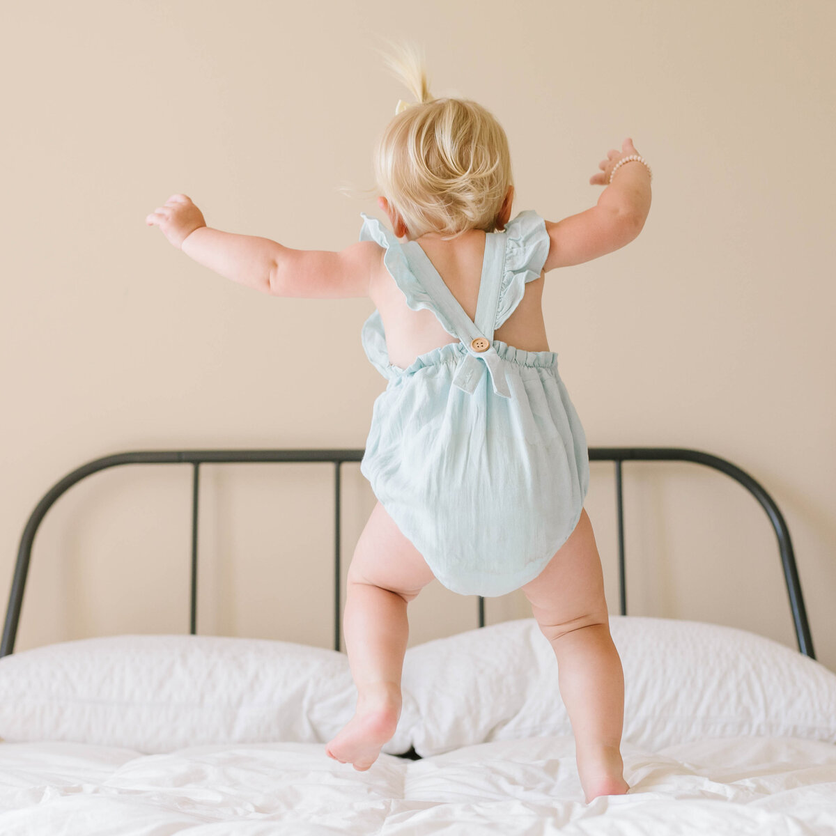 blonde hair toddler jumping on bed