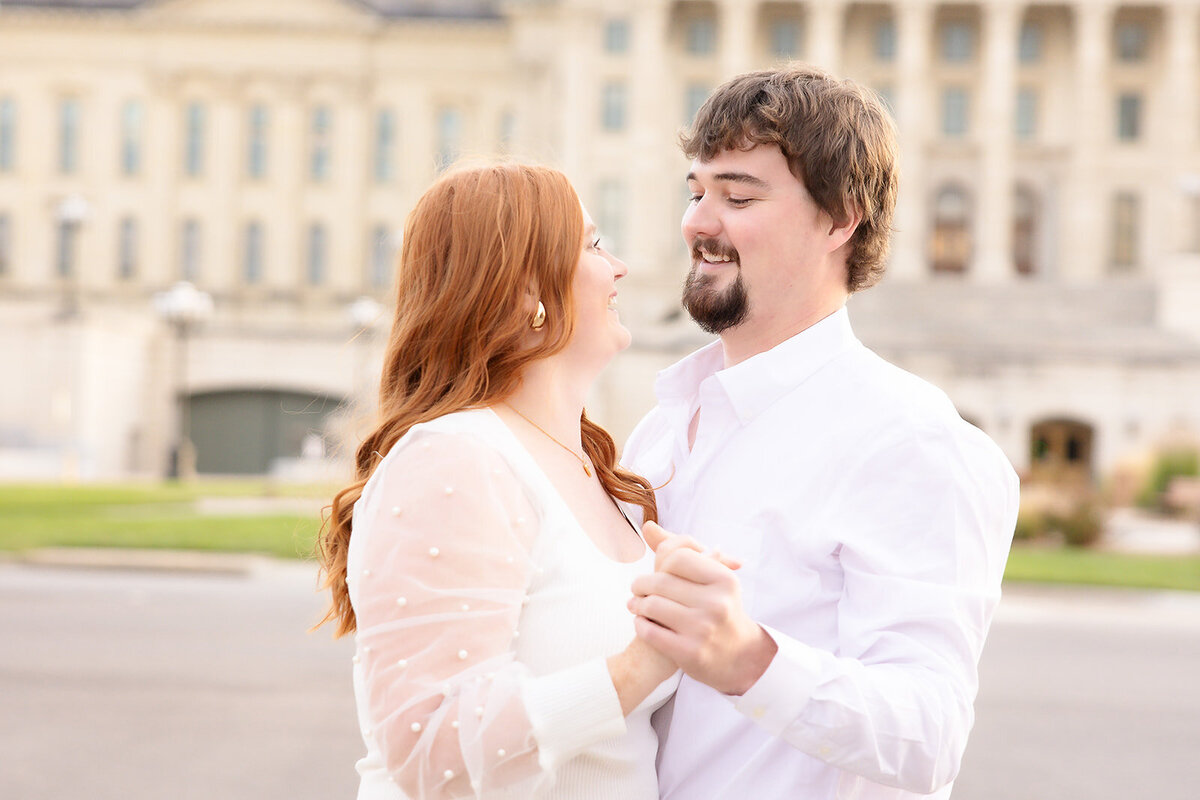 Engaged couple looking into each other's eyes with capitol in background