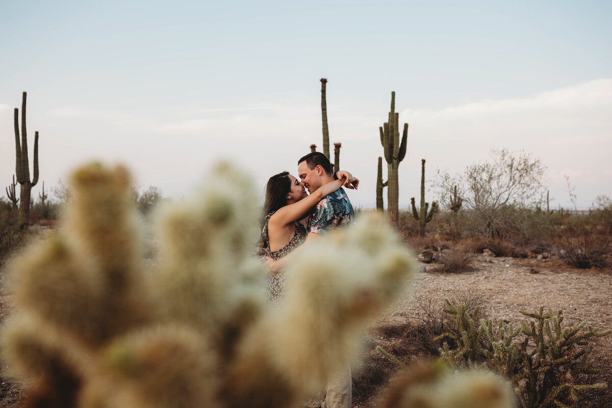 owner of Cactus & Pine Photography and husband kissing in the Arizona desert surrounded by cacti