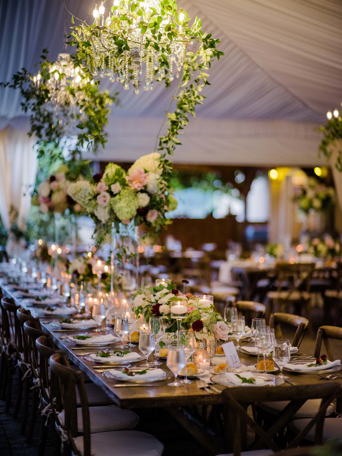 Tall dahlia, rose, and pee gee hydrangea floral arrangements line the long tables.