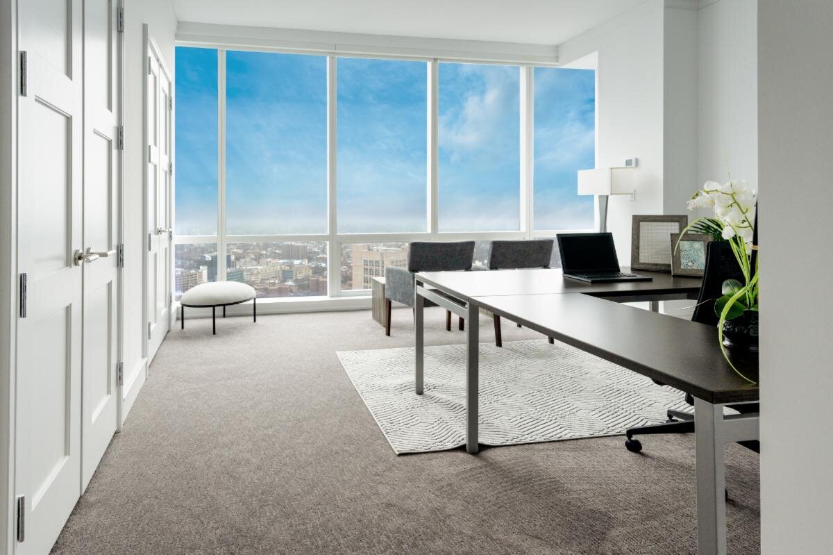 office with L shaped desk and tall windows