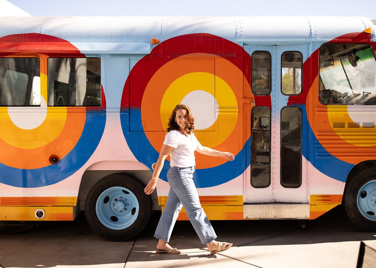Woeman walks in front of colrful bus during her photoshoot with branding photographer/