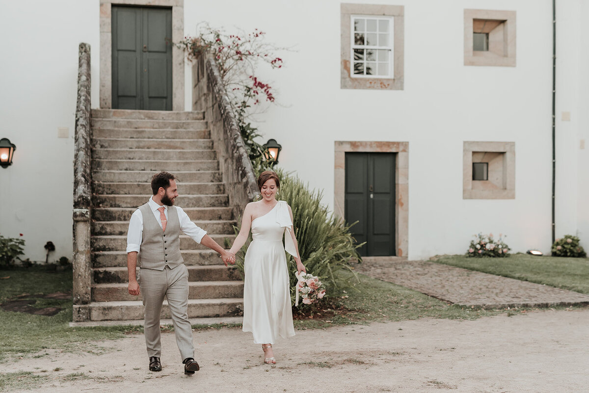 Bride & Groom walking hand in hand in front of the steps of Casa Grande de Fontao at their wedding in Portugal