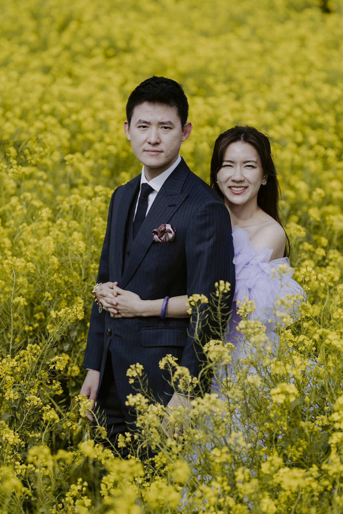 the bride back hugging the groom in the yellow canola fields in jeju island