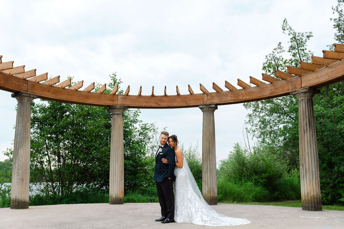 a full length photo of  a bride and groom embracing on the grounds of Eaton Hall in Toronto.  Captured by Ottawa wedding photographer JEMMAN Photography