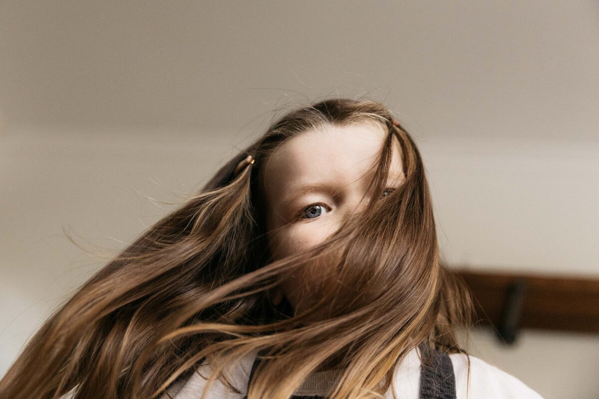 Toddler girl is dancing with her hair moving across her face.