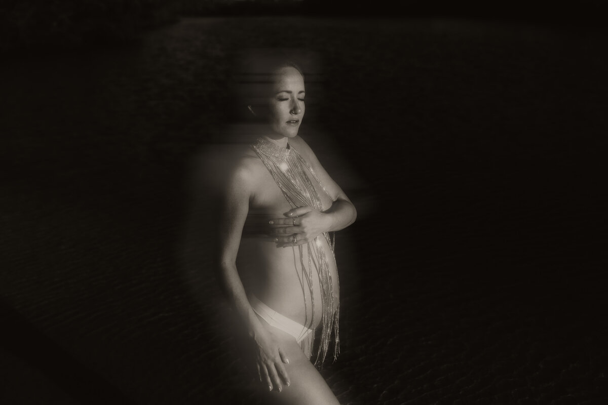 stunning artsy black and white maternity portrait taken in direct harsh light with a women wearing a rhinestine choker over her baby bump during a maternity shoot