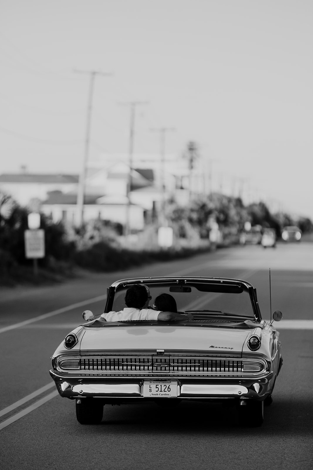 1962 MERCURY MONTEREY photographed from behind. Car is driving on Folly Beach road. Charleston Engagement Photographer created vintage  charm photo.