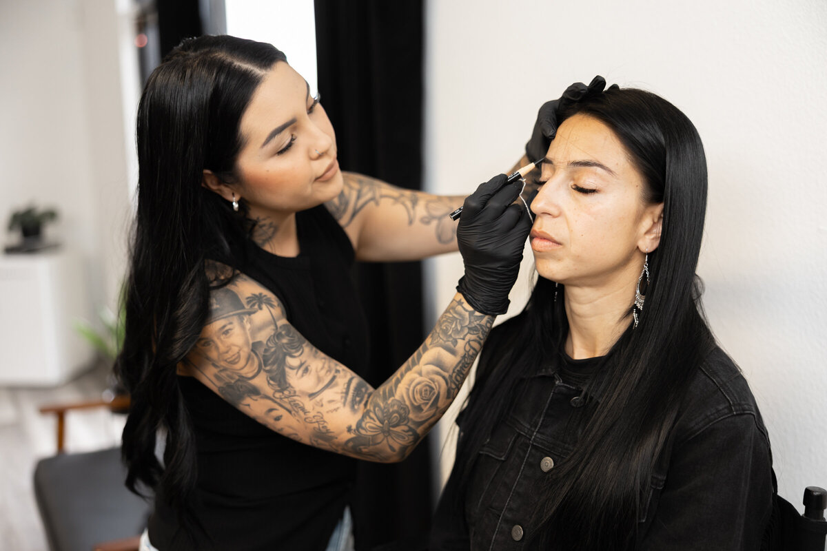 Beauty professional in black lace top smiling while preparing for a client session. Photograph by Yucaipa branding photographer Kaitlyn Dawn Photography.