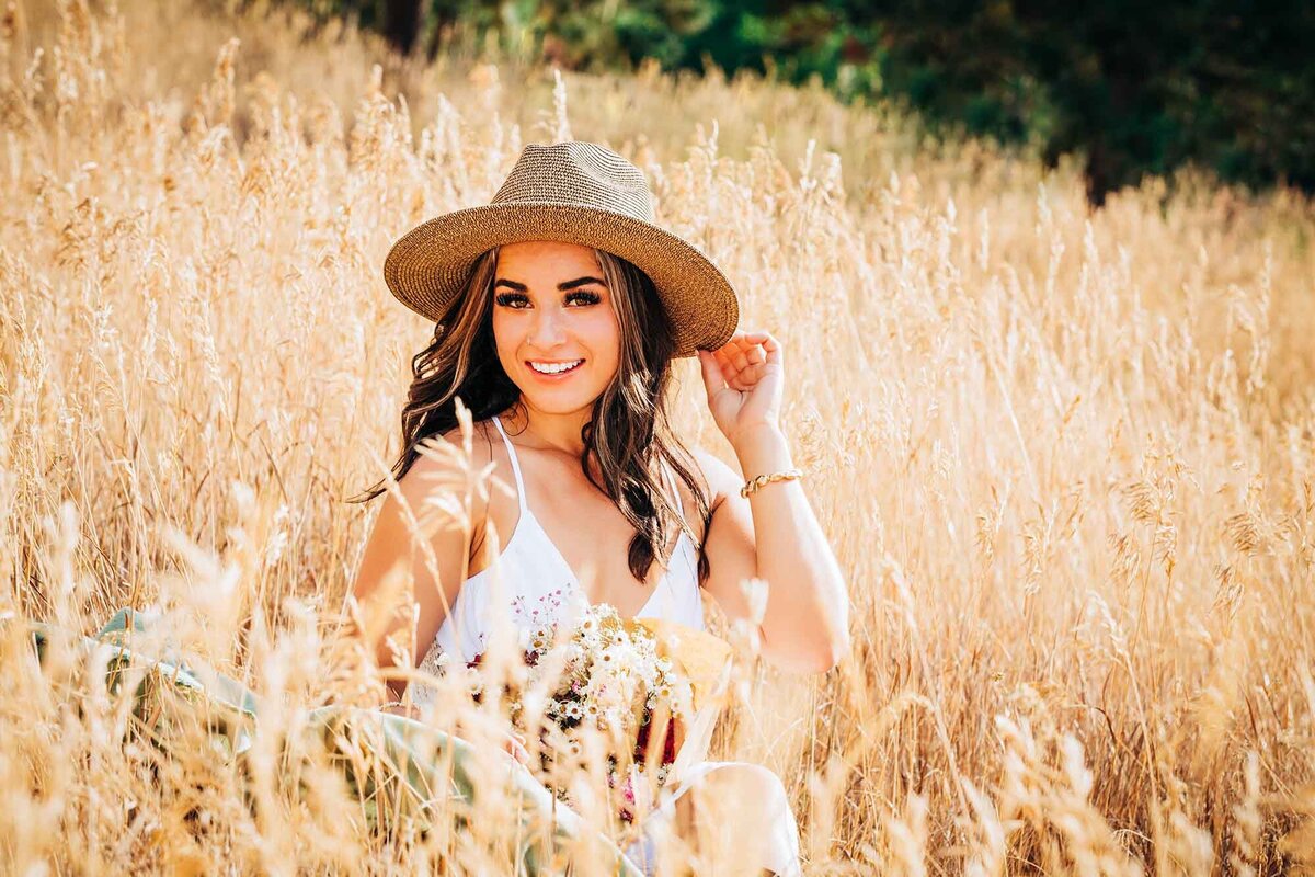 Senior picture Missoula girl with sun hat sitting in field