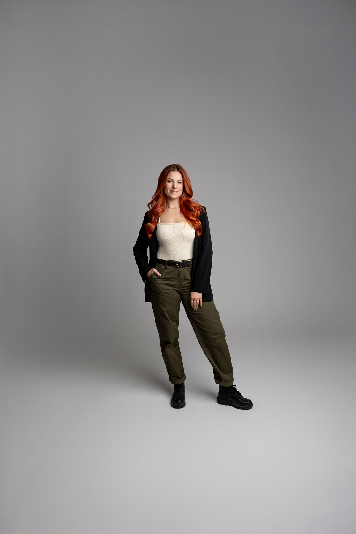Smiling red-haired woman posing with relaxed stance in professional studio portrait. Photograph by Yucaipa branding photographer Kaitlyn Dawn Photography.