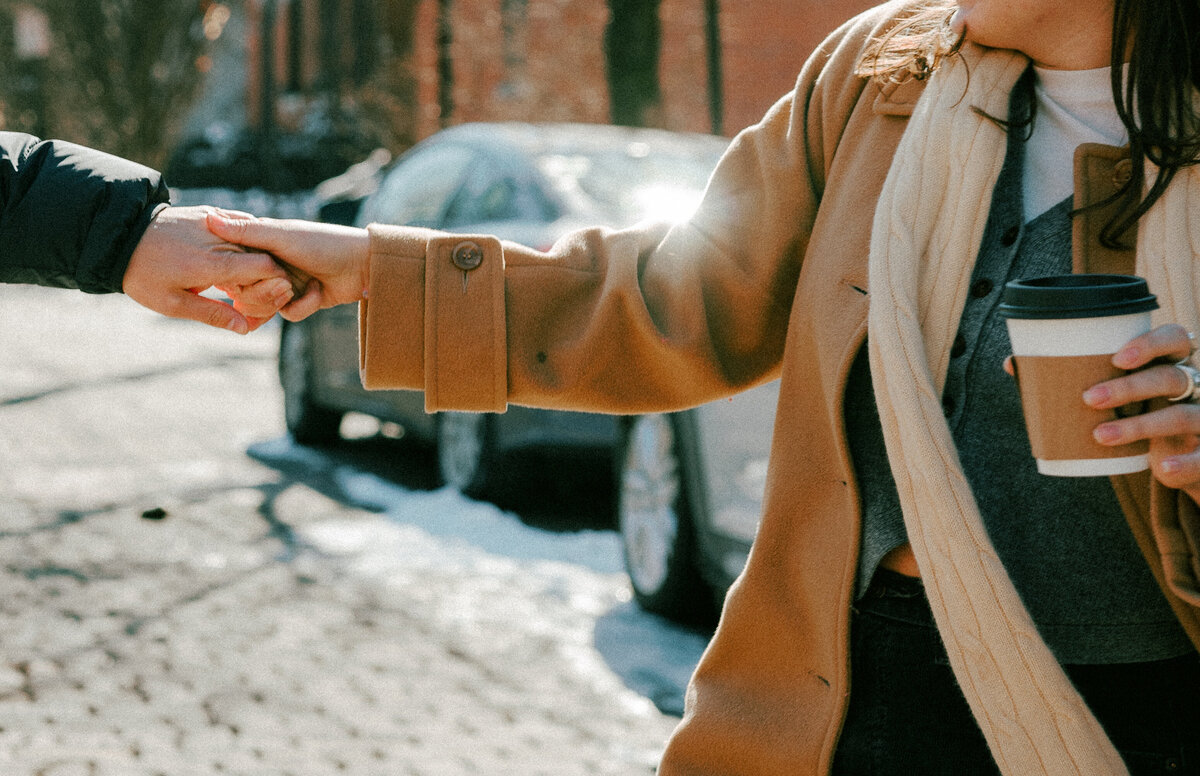 woman holding a cup of coffee and partner's hand
