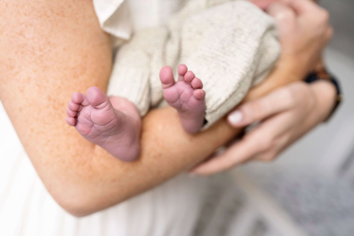 Close-up detail of baby's feet in mother's arms