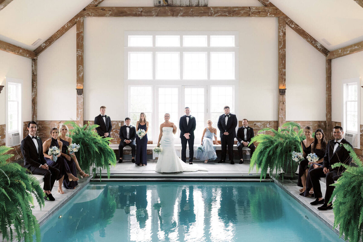 The bride, groom, bridesmaids, and groomsmen are inside the Pool Barn at Lion Rock Farm, CT.  Image by Jenny Fu Studio