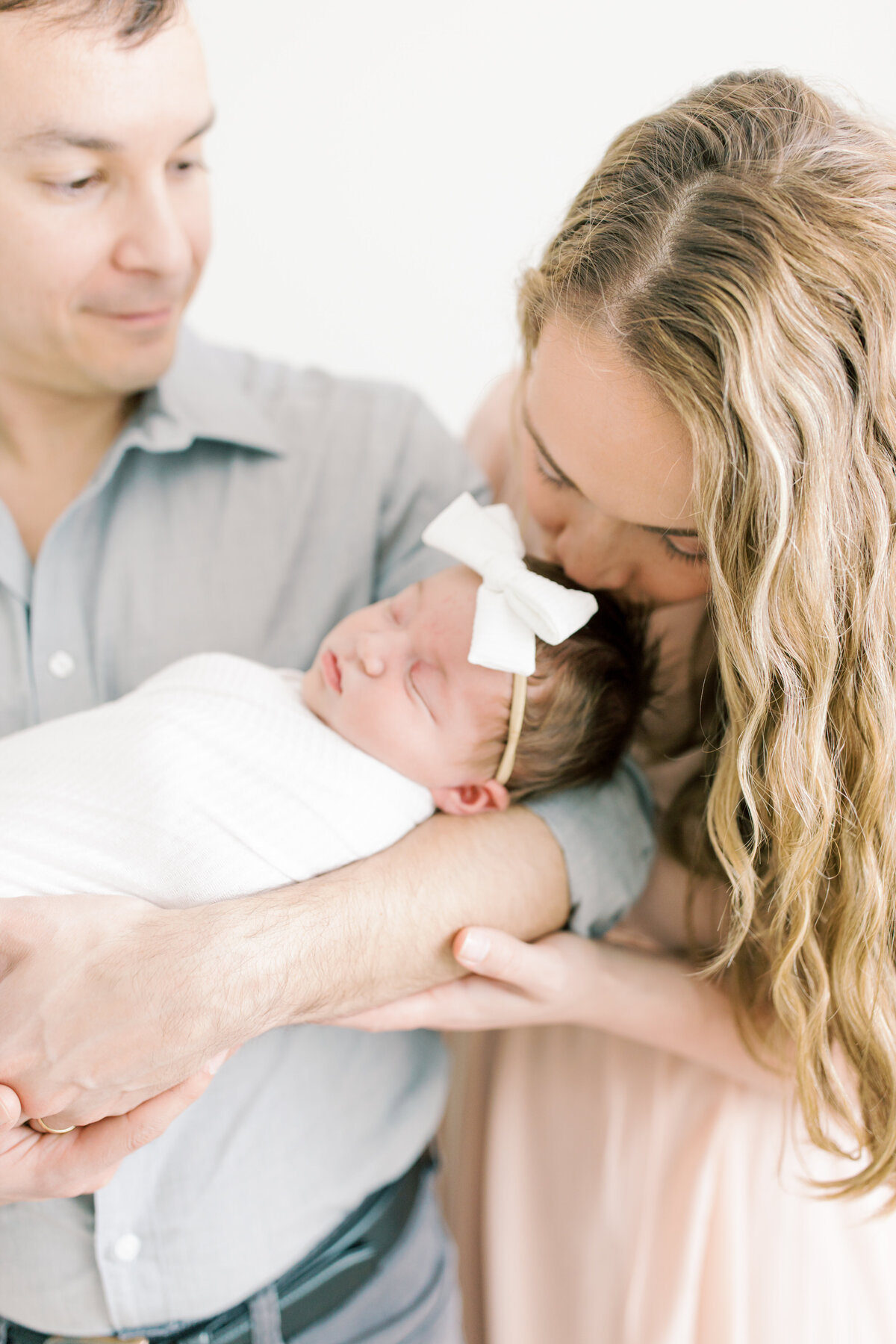 spokane newborn photography image of dad holding newborn and mom kissing her head