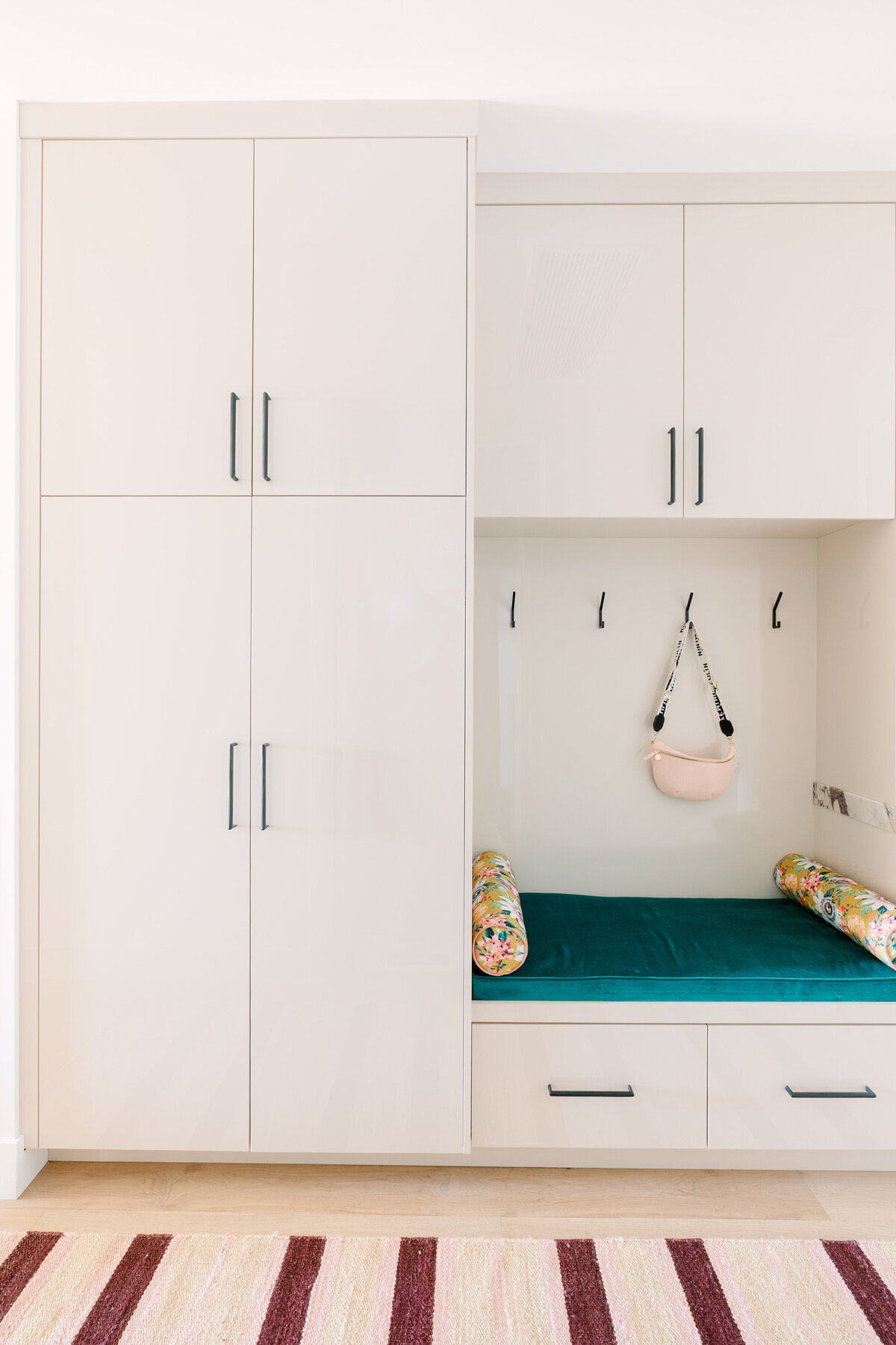 Modern mudroom with beige high gloss cabinets, Calcatta Viola marble counters, and floral cushions.