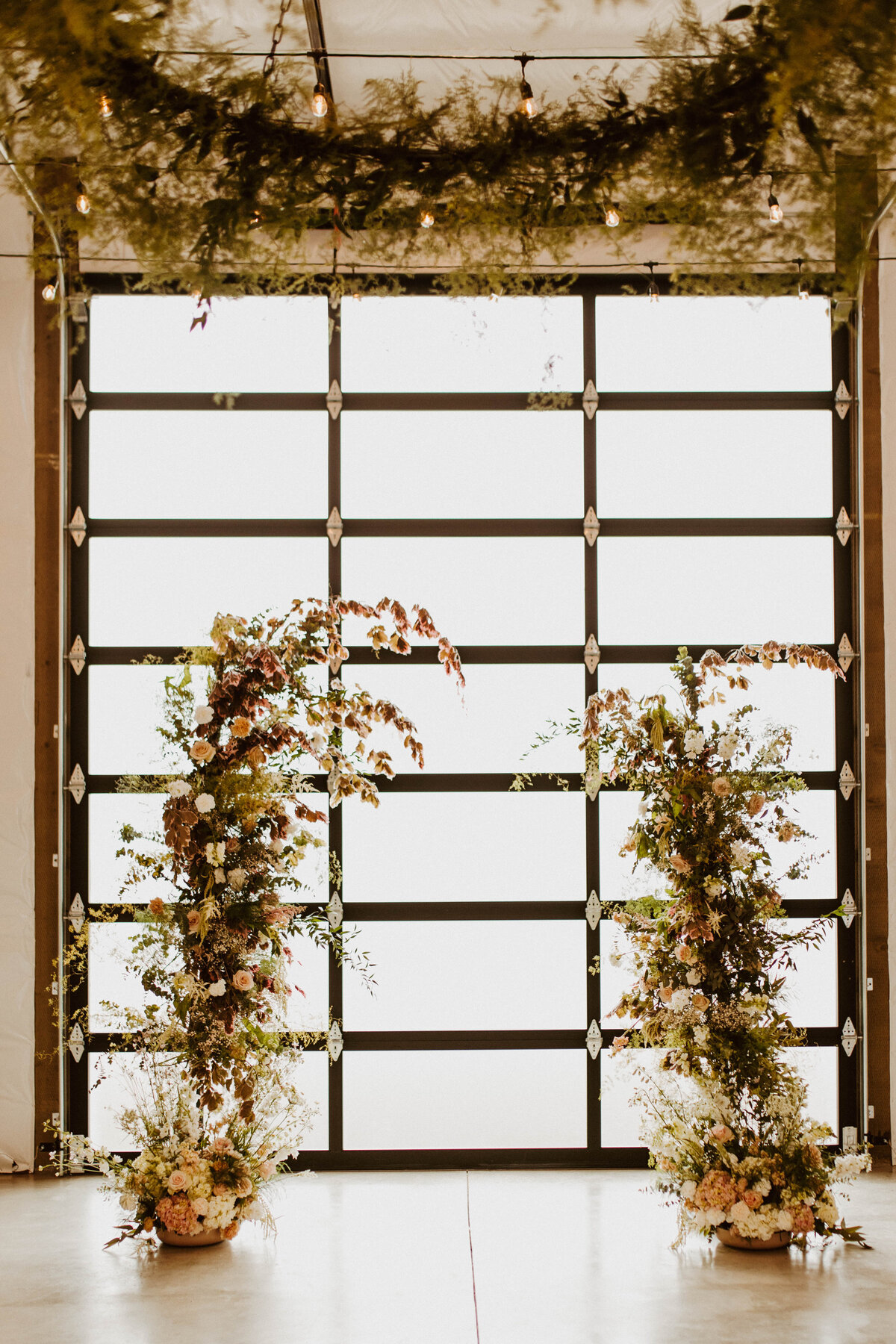 Picture of the glass barn doors, backlit and with a nice greenery altar.