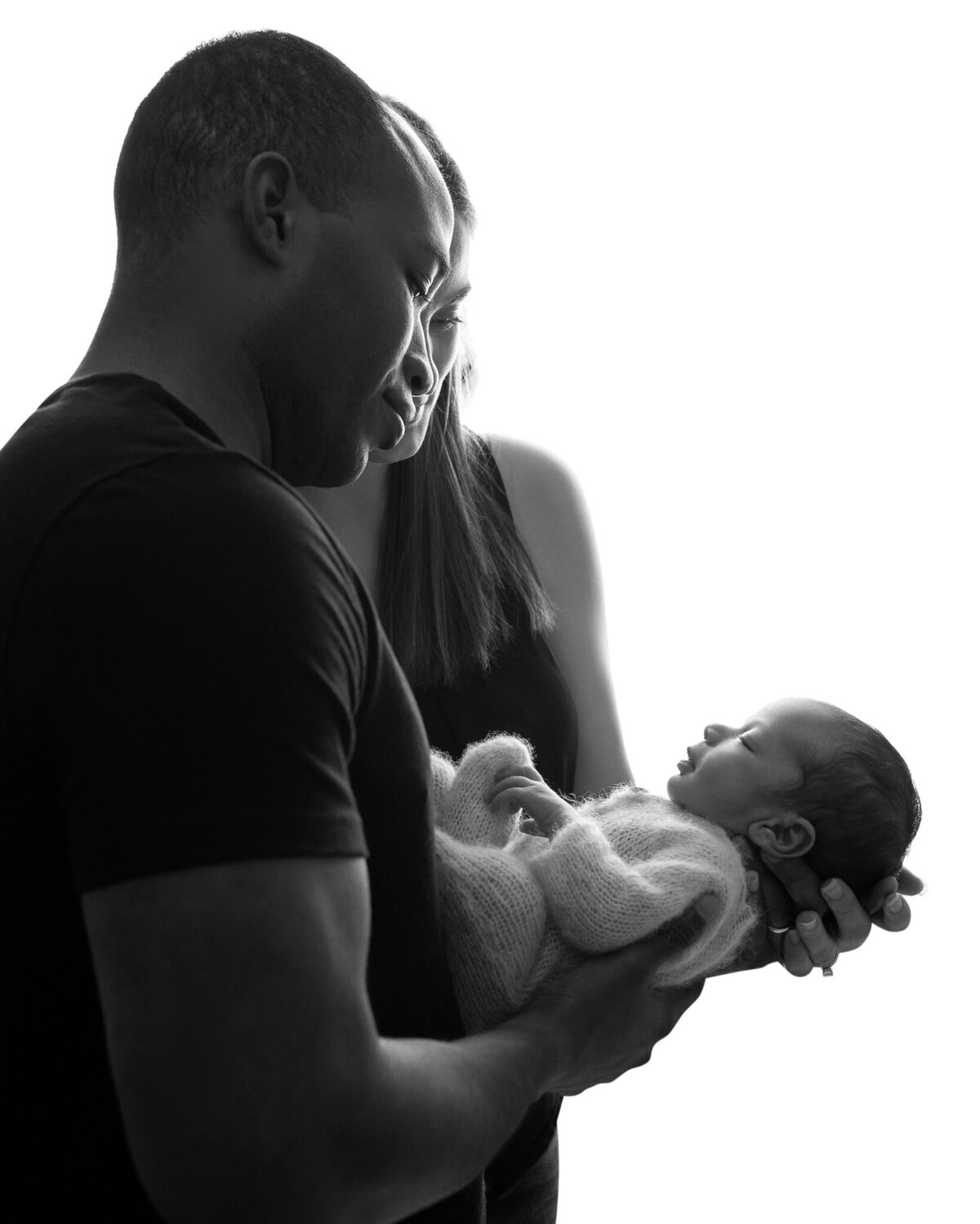 Black and white backlit portrait of parents holding their newborn in a quiet, intimate moment | Austin newborn photographer serving Liberty Hill and beyond