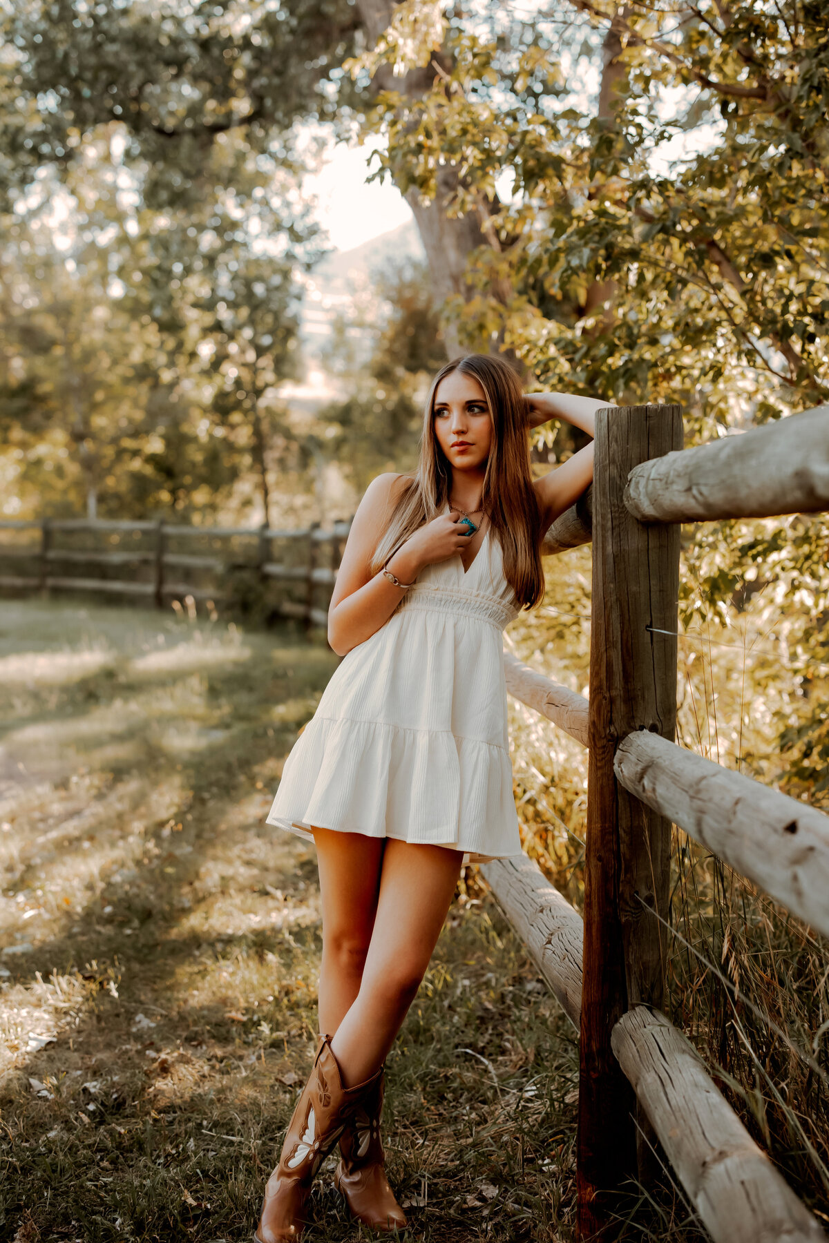 High school senior girl leaning against a wooden fence in Boulder Colorado