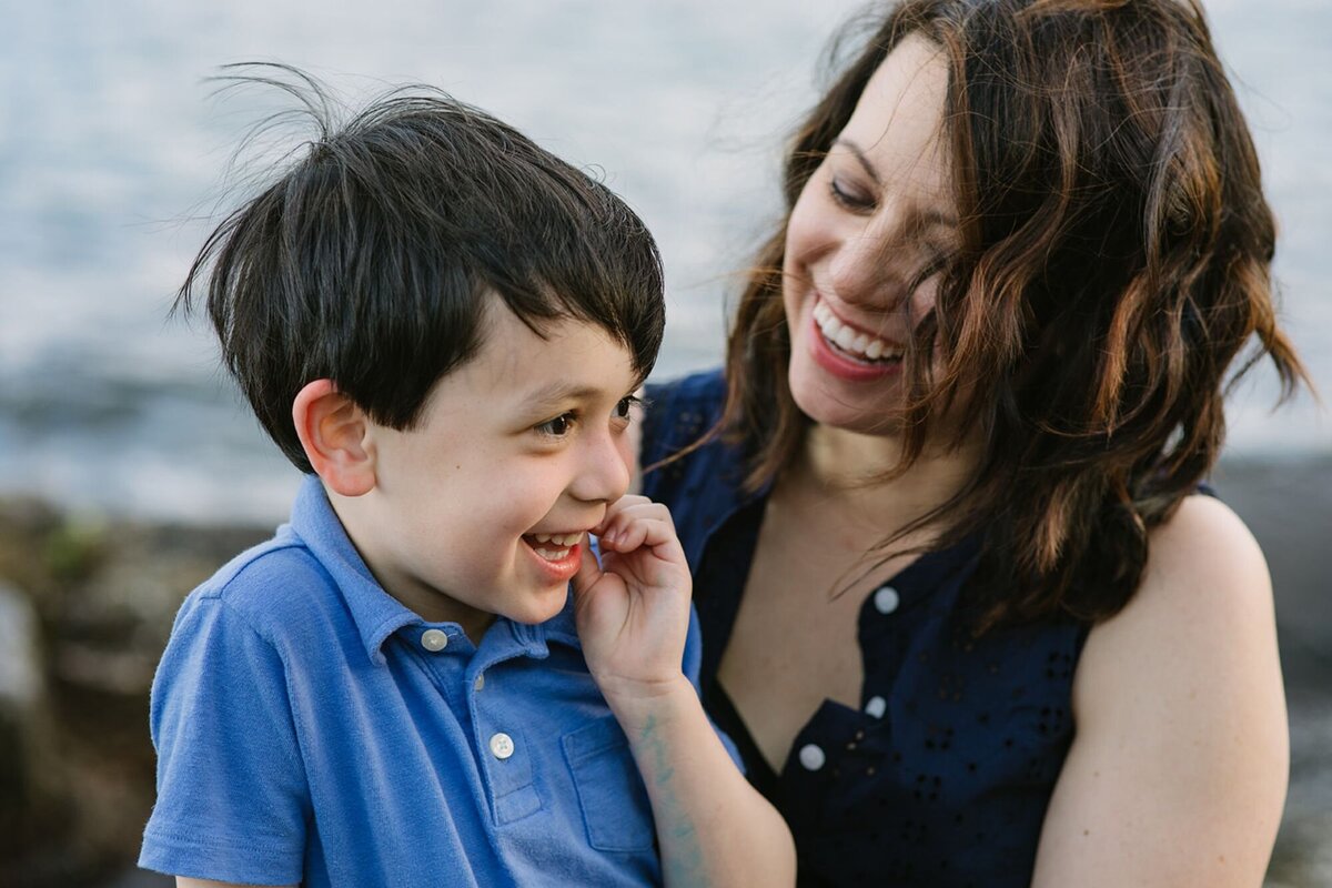 A mother holds her son as they are laughing.