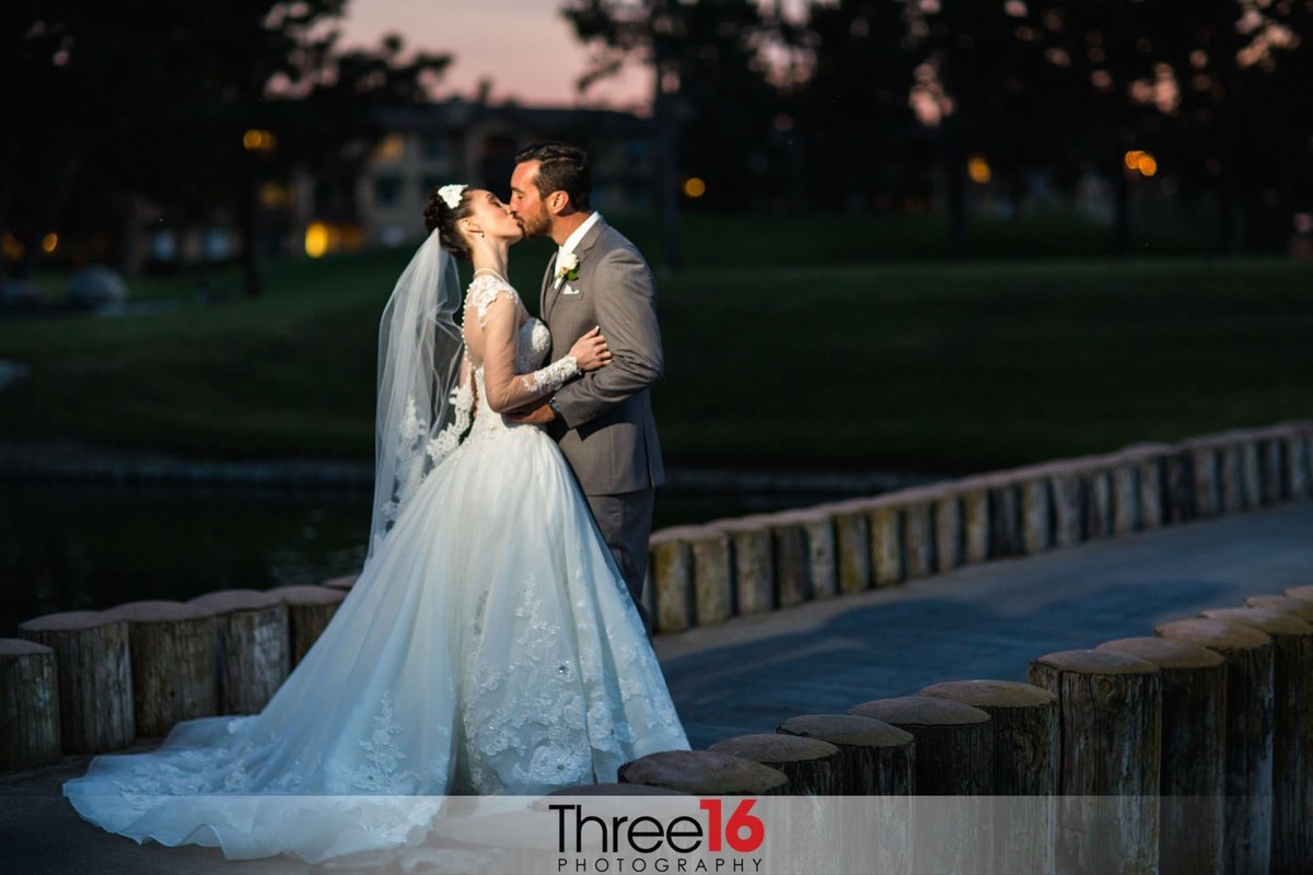 An evening kiss between the newly married couple on a golf course bridge