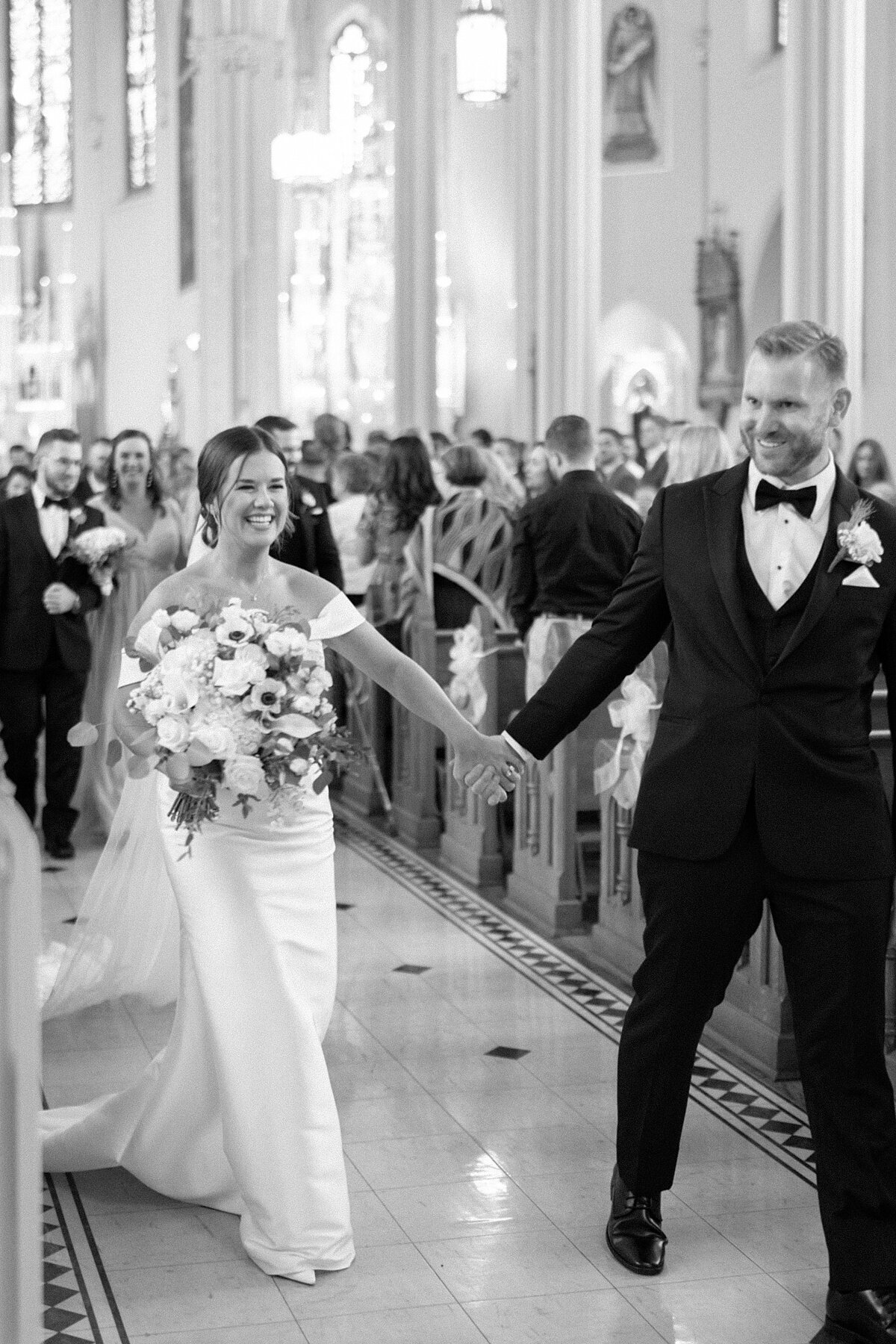 Bride and groom smiling and holding hands in wedding aisle taken by photography chicago wedding expert Allison Francois Photography
