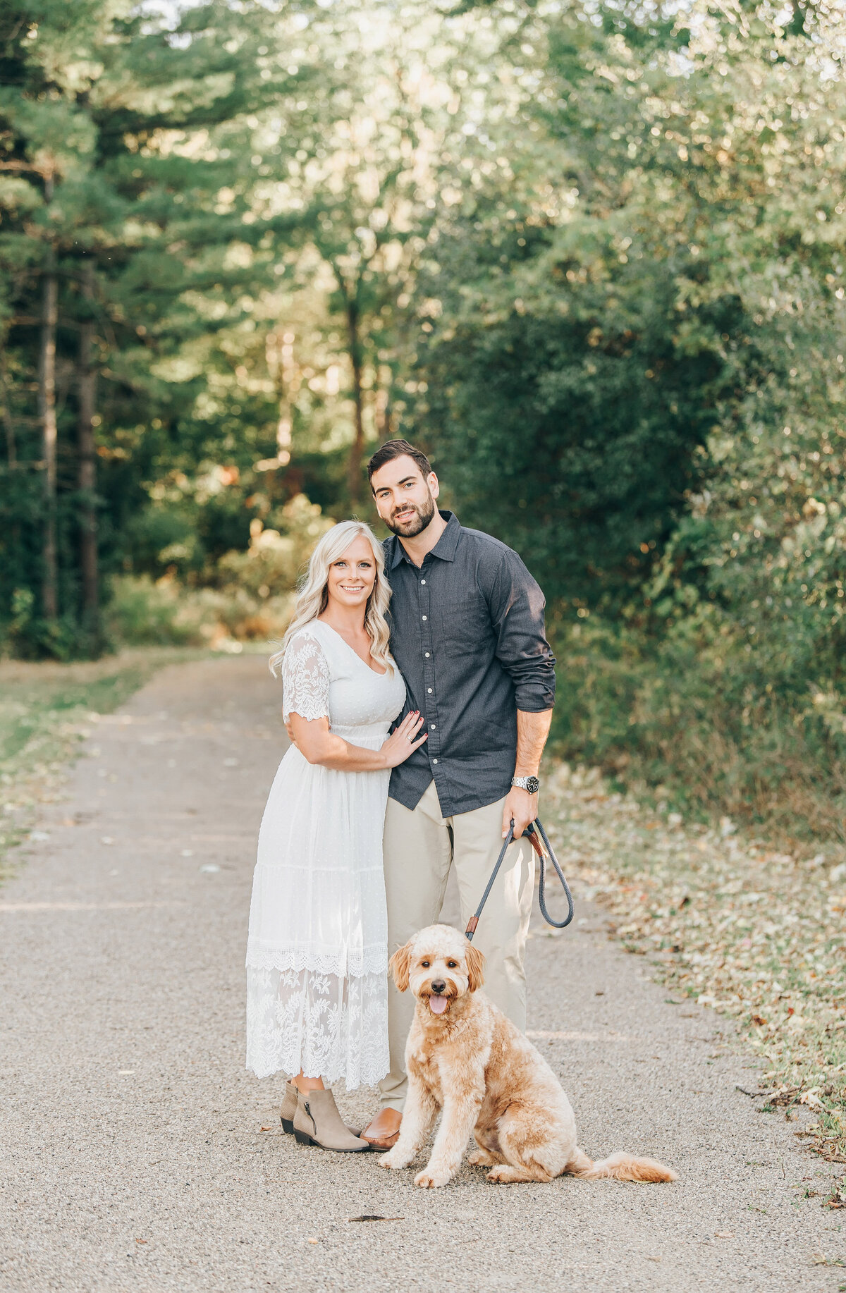 Couple posing with their dog for their forest engagement session in London Ontario