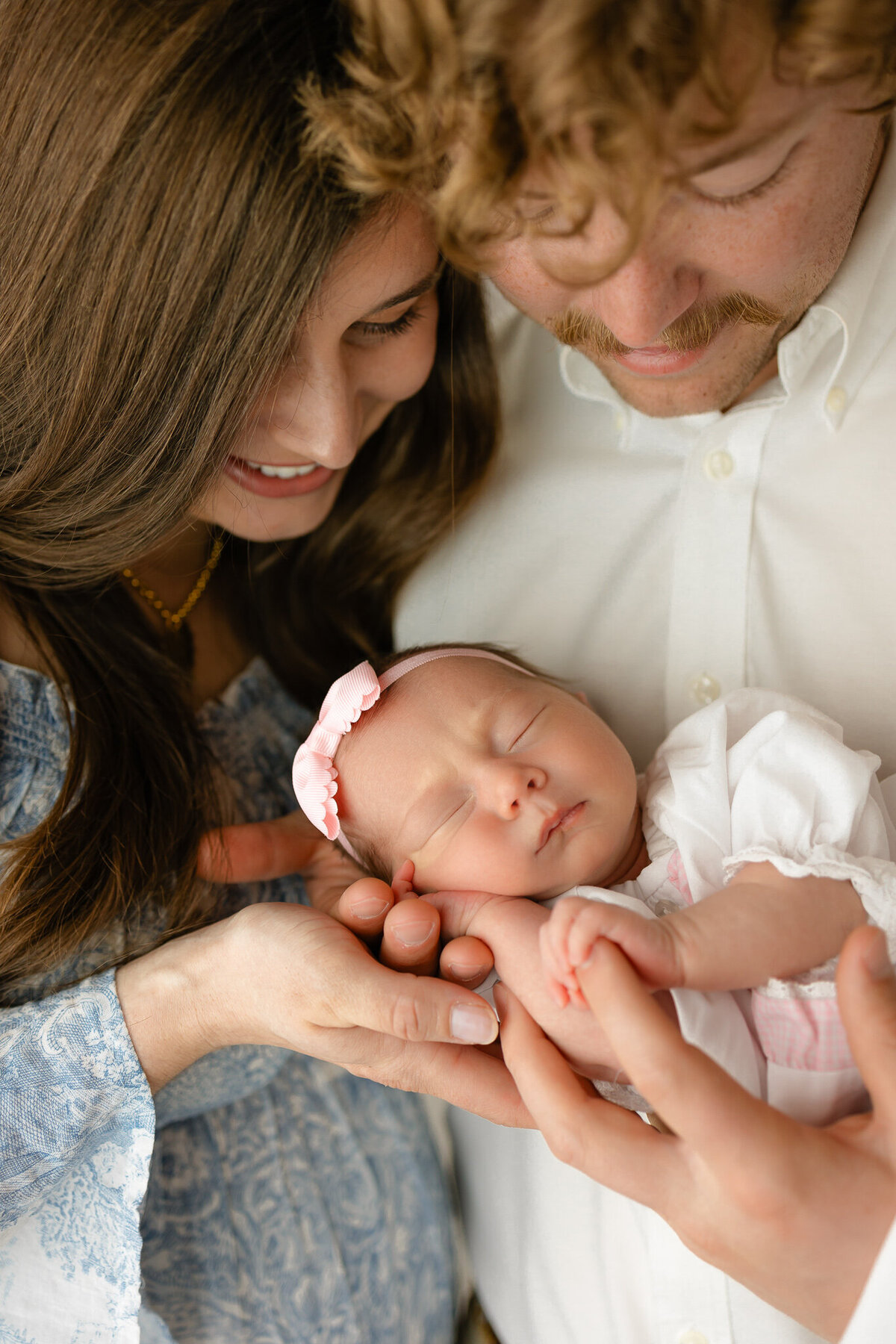 Young family wearing blue and white outfits of 3 holding their newborn baby girl in Savannah, Ga