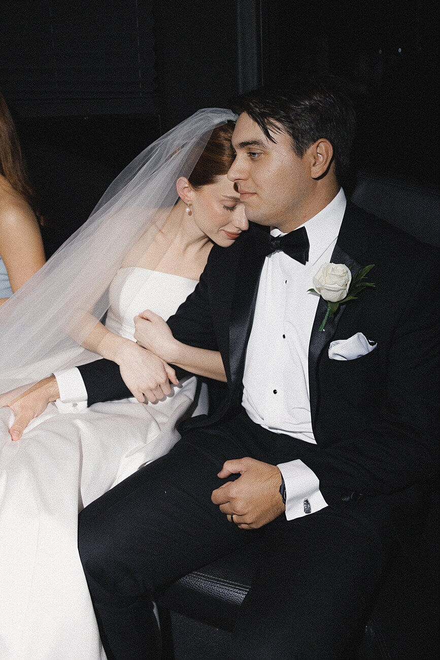 bride snuggling up under the groom on the party bus