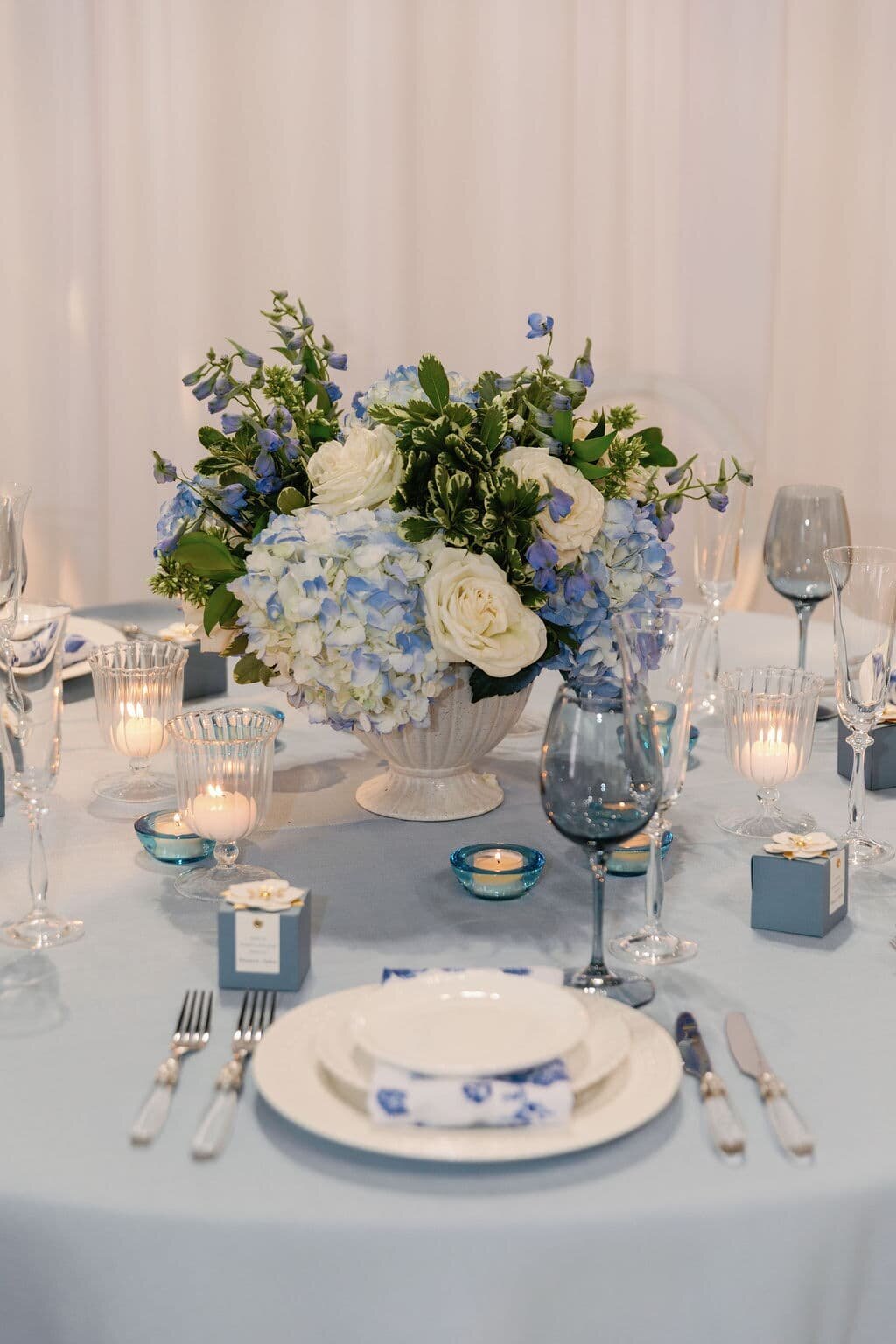 Close-up of a beautifully arranged wedding table with a blue and white floral centerpiece, including hydrangeas and roses, designed by a Maryland wedding florist.