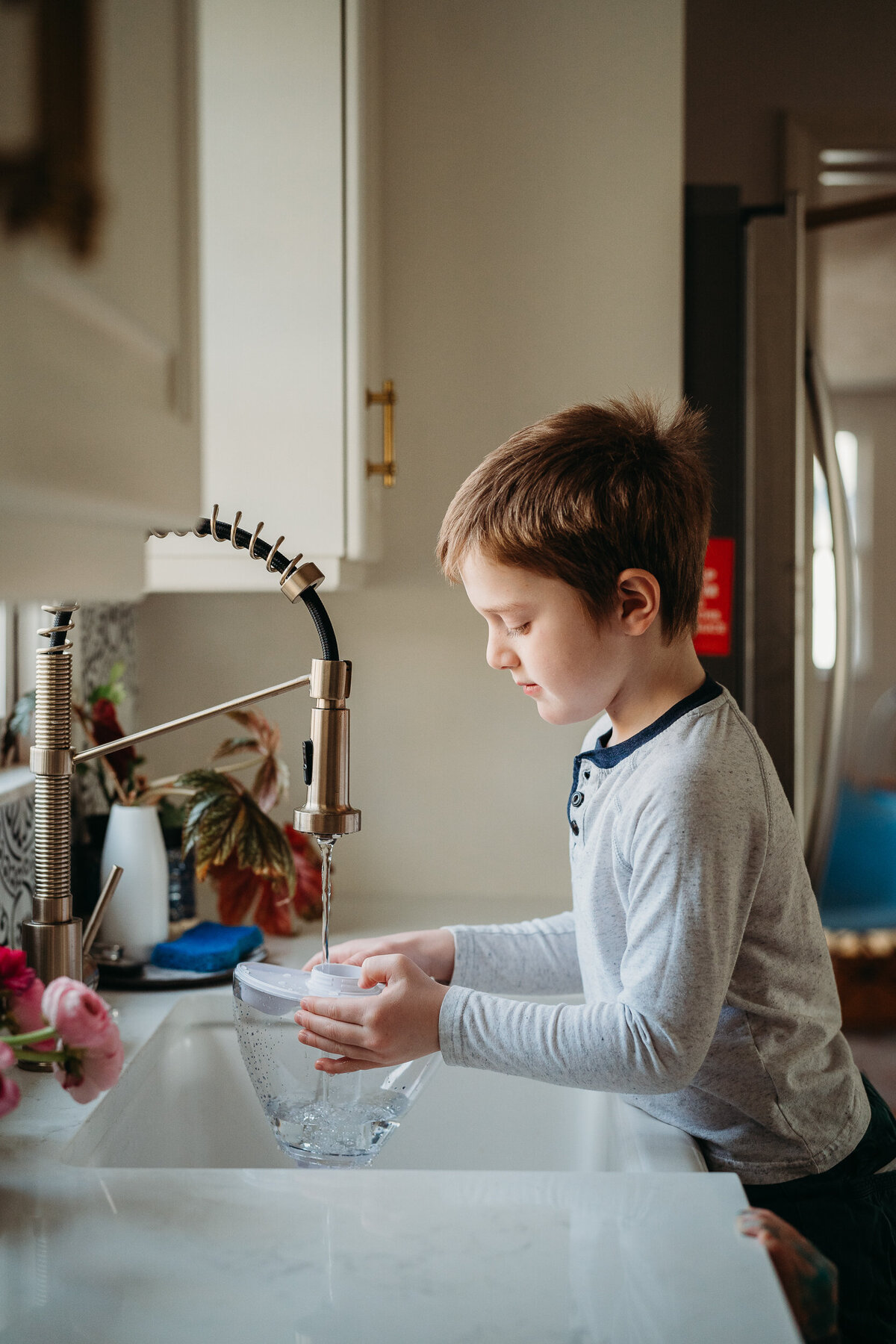 boy fills humidifier top in kitchen sink