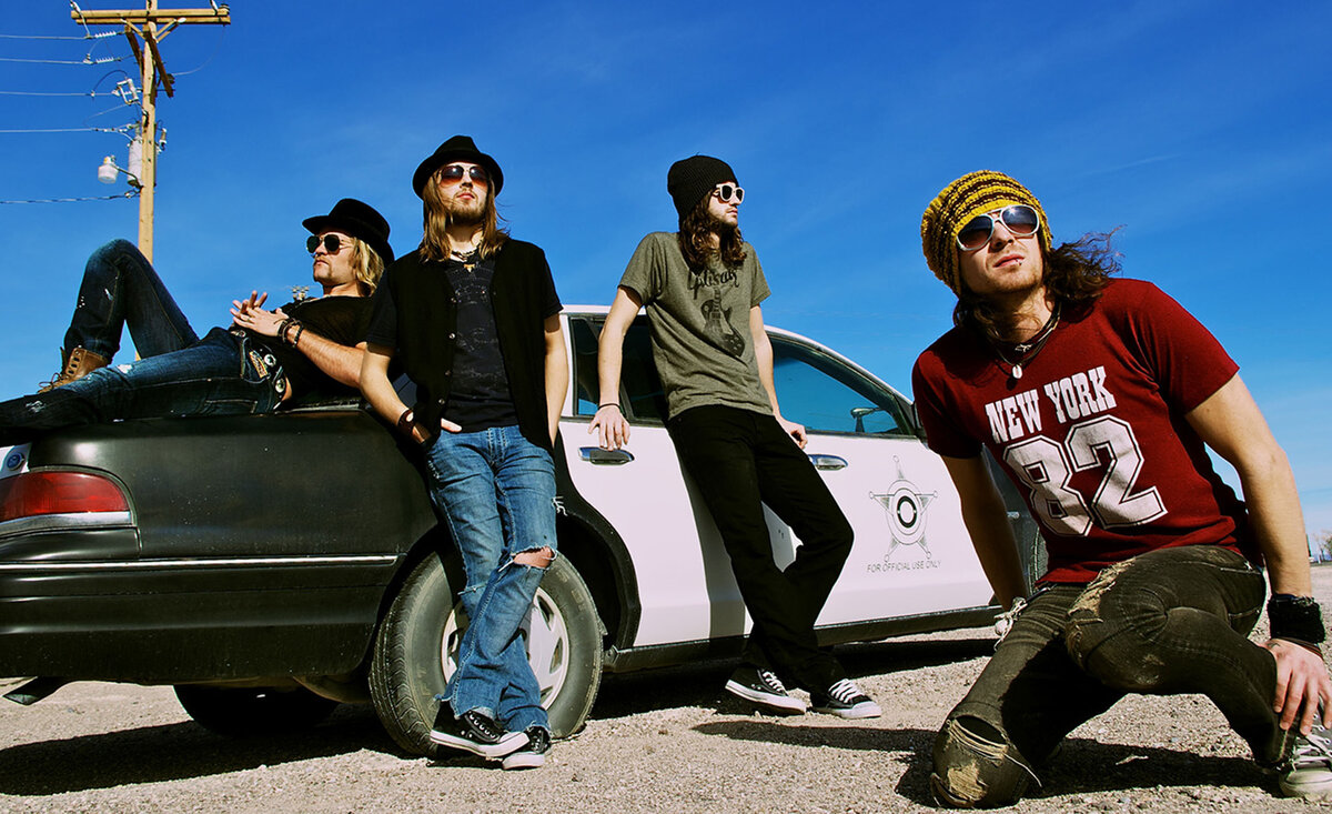 Music band photo One Bad Son leaning against police car one member kneeling close up