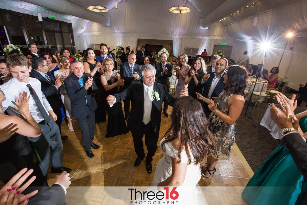 Bride dances with her father as guests surround them