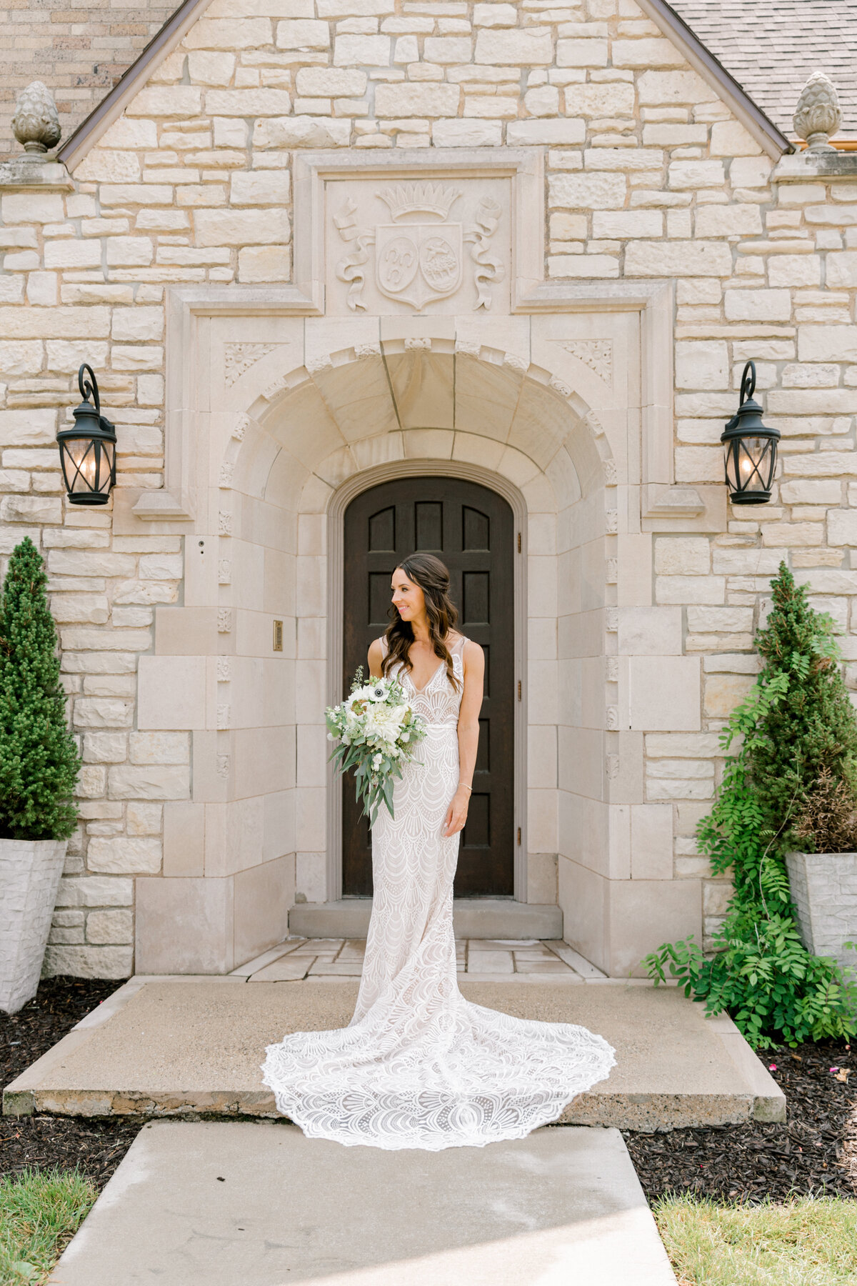 bride standing in front of venue with bouquet