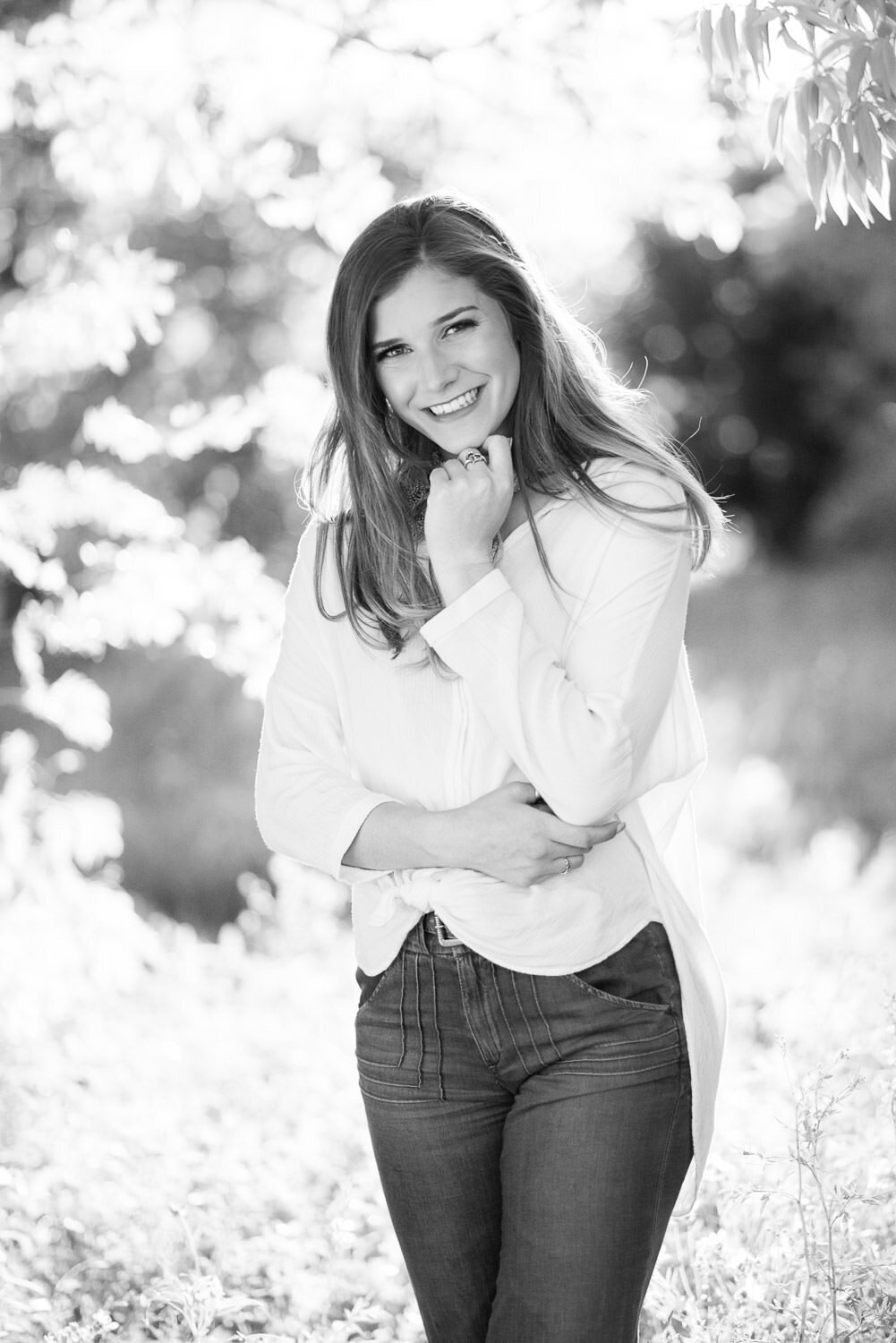 Outdoor senior portrait of a girl smiling at the camera, wrapped in warm natural sunlight.