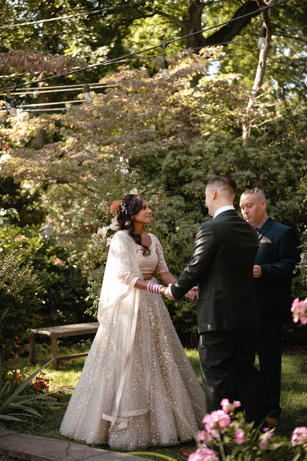 Bride and groom in a classic black suit exchange vows in a romantic outdoor setting.