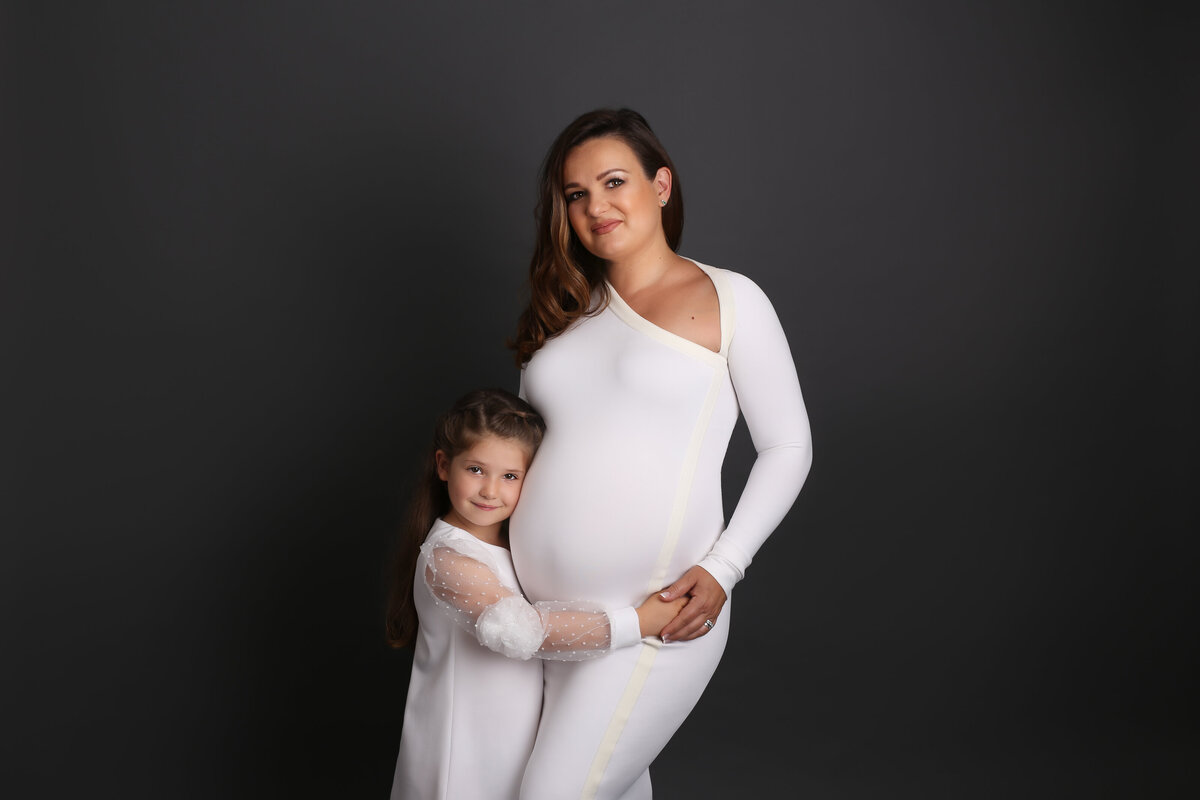Pregnant mother & her daughter both dressed in white dresses