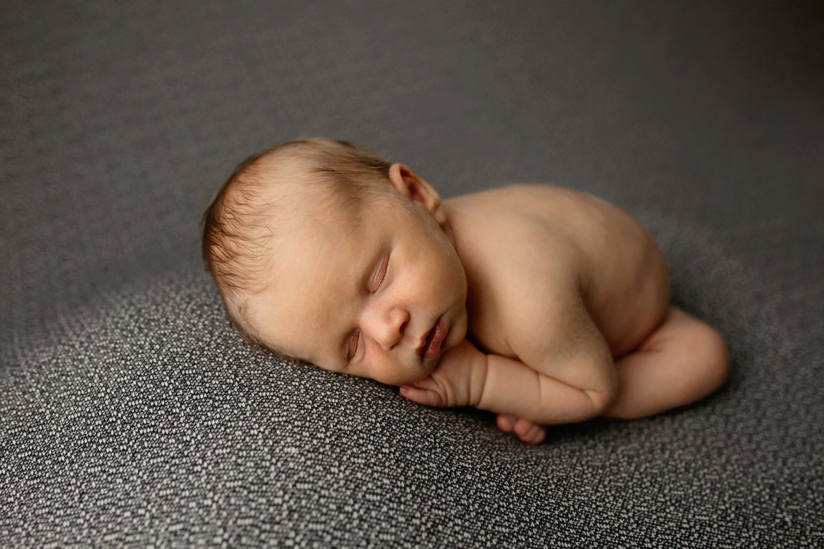 newborn boy posed on gray blanket