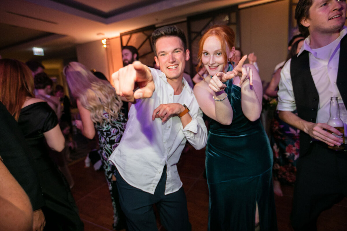 A man and woman are posing for a picture and the man is pointing at the camera