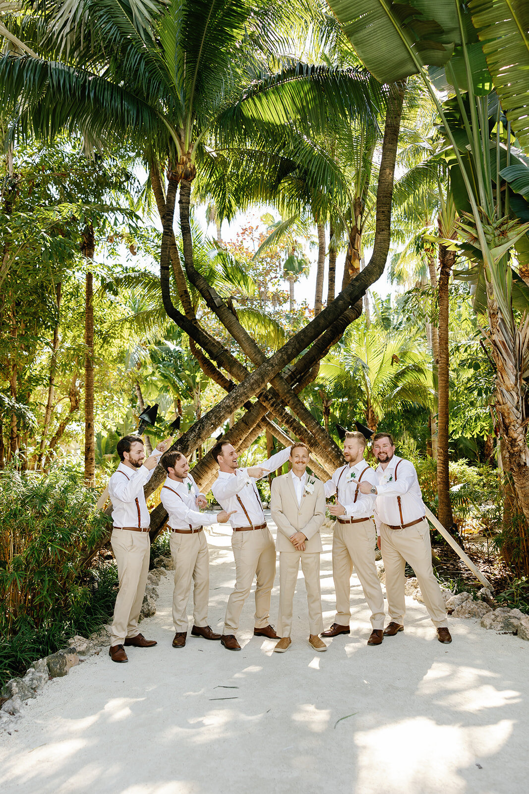 Hunter and his groomsmen share a candid moment in a tropical garden setting.