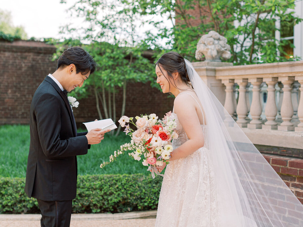 Groom reading vows while bride laughs