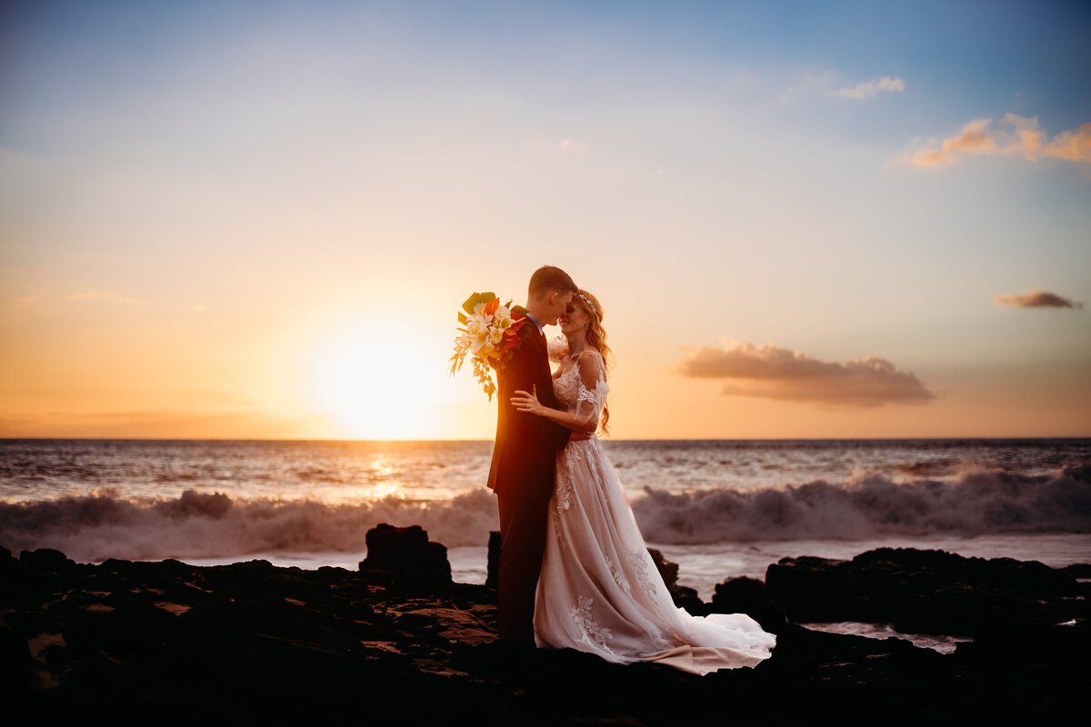 Bride and groom kissing at sunset on the  beach in Hawaii