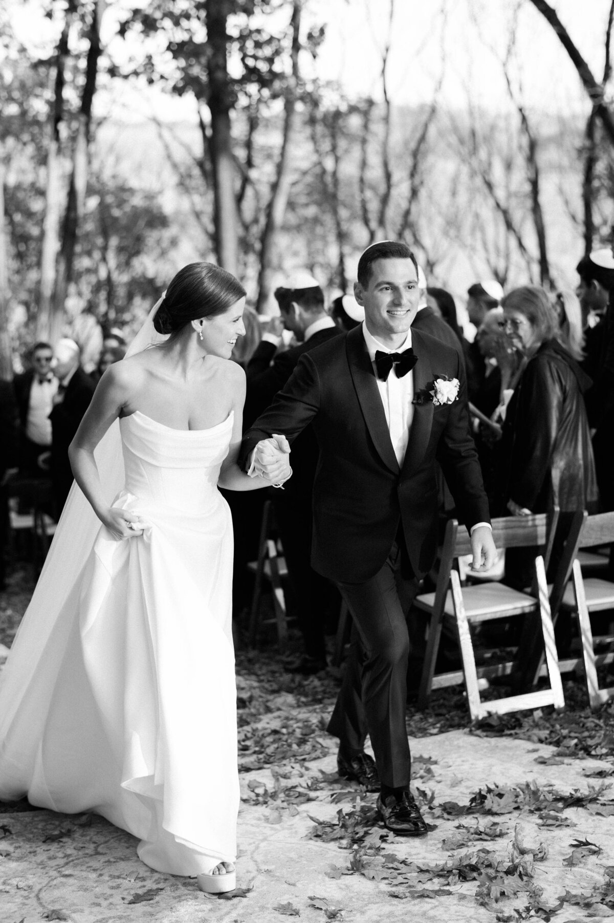 The newlyweds, hand in hand, walk down the aisle after their outdoor ceremony, beaming with joy