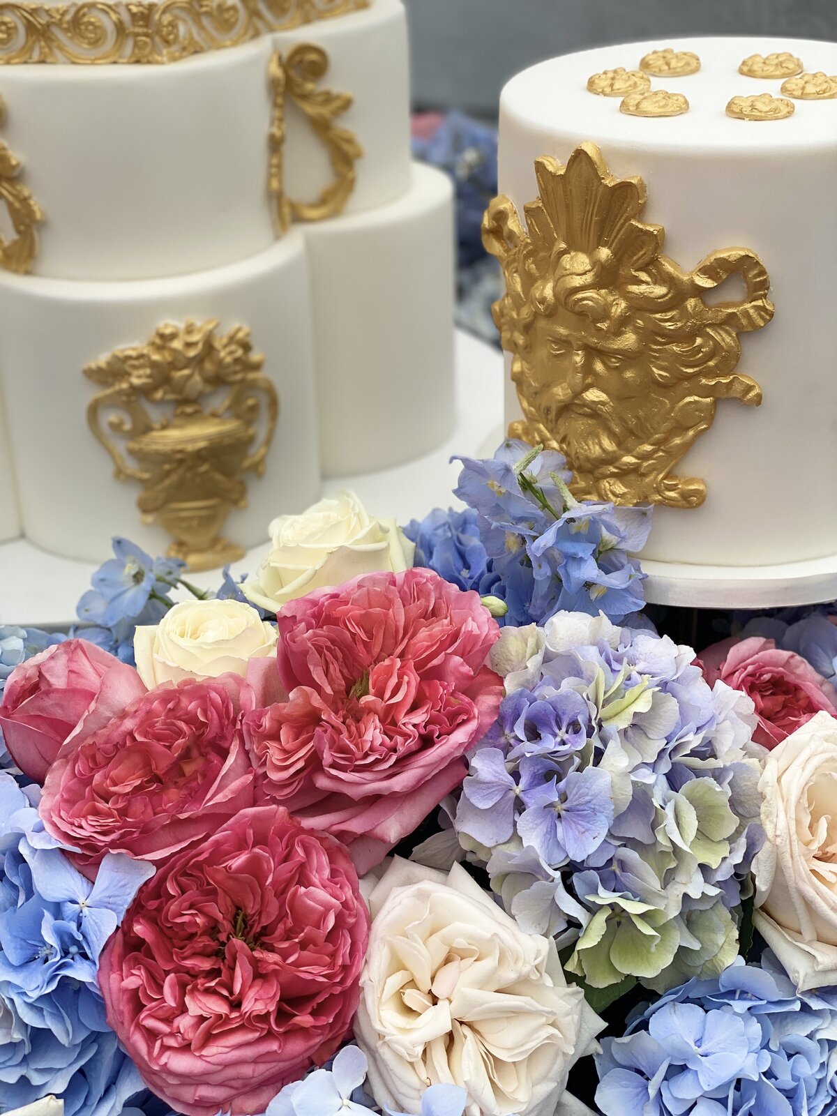 Gold and white wedding cake with fresh flowers