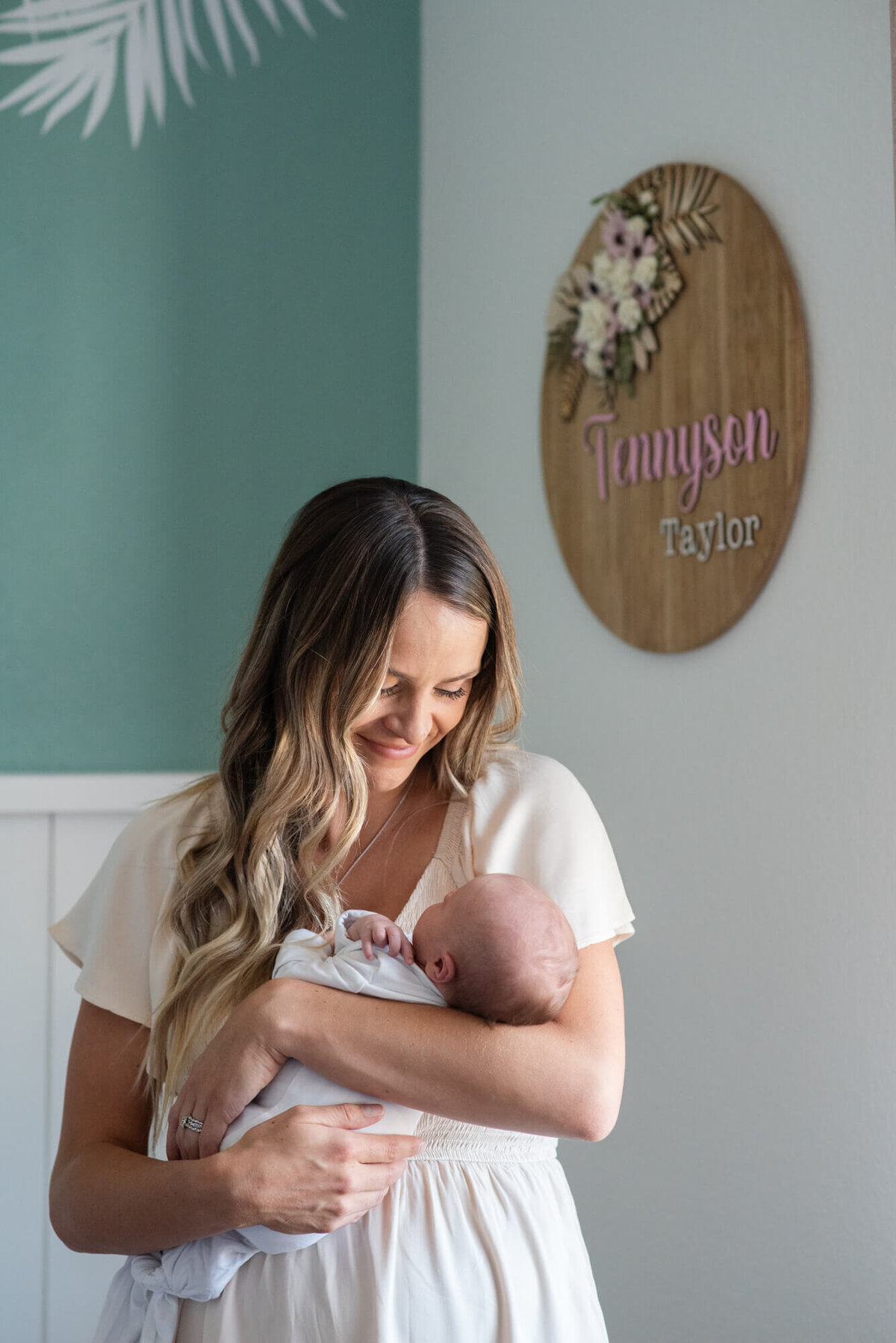 Mother smiling down at her newborn baby in her arms while standing in a nursery