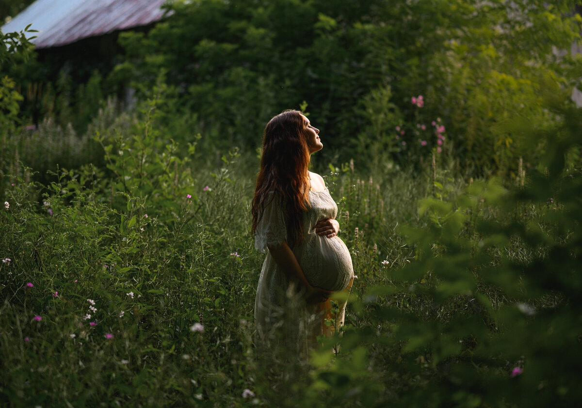 Mom wearing a white maternity dress in a field in Richmond