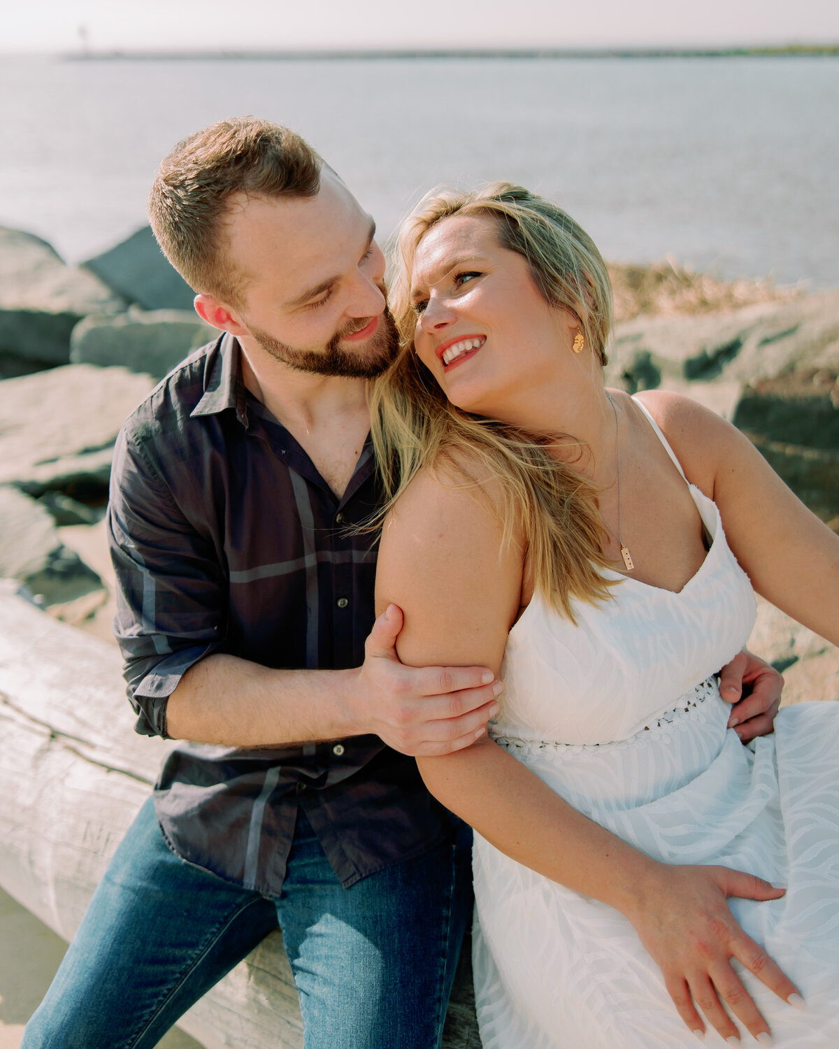 A couple sitting down and smiling as one leans back into the other 