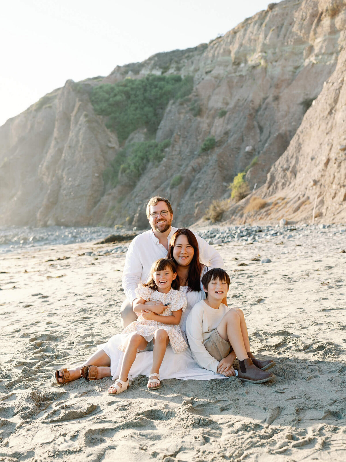 family photo sitting on a blanket at the beach